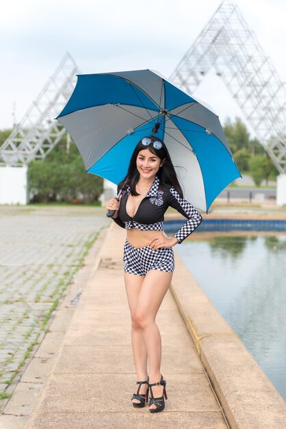 Bella donna asiatica sexy in vestito nero con l'ombrello all'aperto Ritratto di stile del vestito da corsa abbastanza tailandese