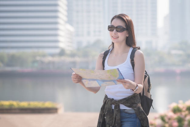 Bella donna asiatica solista turistica guardando la mappa alla ricerca di luogo turistico.