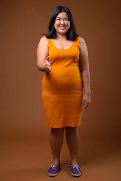 bella donna asiatica sovrappeso che indossa un abito senza maniche arancione