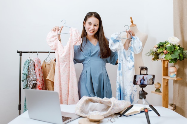 Bella donna asiatica Streaming live per la vendita di vestiti online con lo smartphone nel suo negozio Concetto di mercato online del proprietario di una piccola impresa