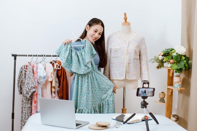 Bella donna asiatica Streaming live per la vendita di vestiti online con lo smartphone nel suo negozio Concetto di mercato online del proprietario di una piccola impresa