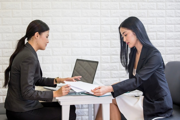 Bella donna asiatica usando il portatile per lavorare insieme con il partner