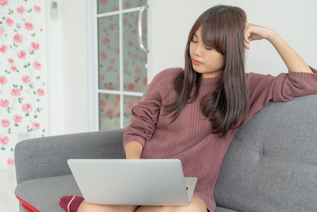 bella donna asiatica utilizzando laptop sul divano nel soggiorno