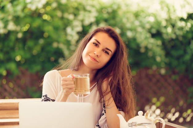 Bella donna attraente al caffè con un computer portatile con una pausa caffè