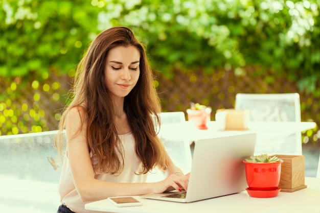 Bella donna attraente al caffè con un computer portatile con una pausa caffè