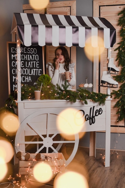 bella donna barista in grembiule a righe tiene in mano una tazza di caffè Vetrina di Capodanno