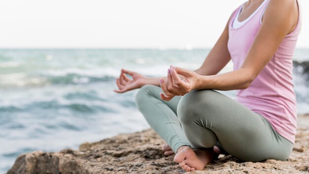 Bella donna bionda che fa yoga in spiaggia