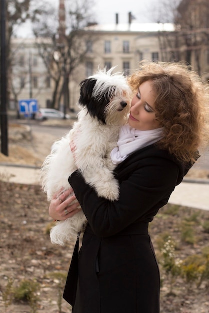 Bella donna bionda che gioca con il cane nel parco