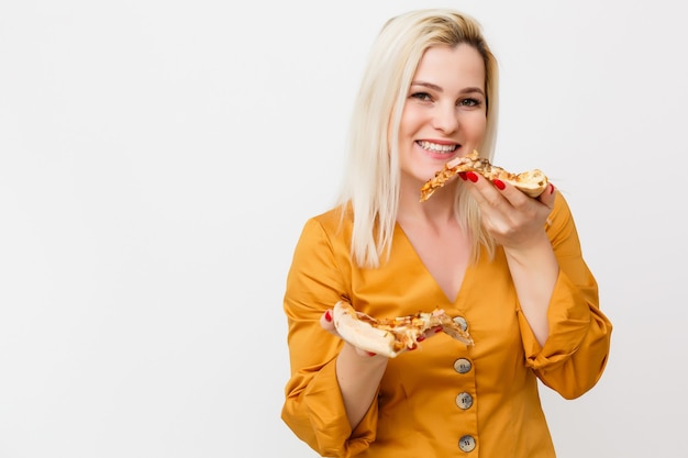 bella donna bionda che mangia un pezzo di pizza