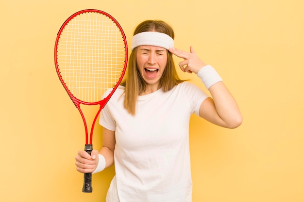 Bella donna bionda che sembra gesto di suicidio infelice e stressato facendo segno di pistola concetto di tennis