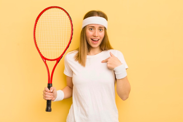 Bella donna bionda che si sente felice e indica se stessa con un concetto di tennis eccitato