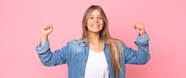 Bella donna bionda che si sente felice, positiva e di successo, celebrando la vittoria, i risultati o la buona fortuna