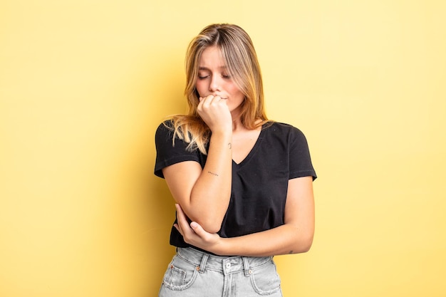 Bella donna bionda che si sente seria, premurosa e preoccupata, fissando di lato con la mano premuta contro il mento