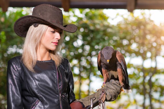 Bella donna bionda che tiene un harris hawkon un guanto protettivo