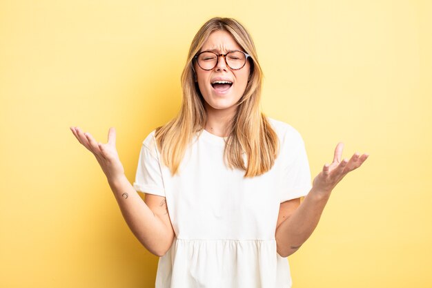 Bella donna bionda che urla furiosamente, si sente stressata e infastidita con le mani in aria dicendo perché me