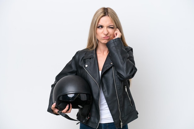 Bella donna bionda con un casco da motociclista isolato su sfondo bianco frustrato e che copre le orecchie
