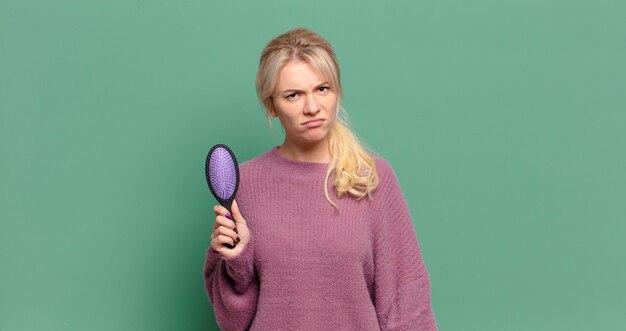 Bella donna bionda con una spazzola per capelli