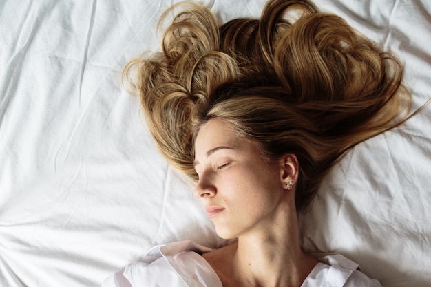 Bella donna bionda del ritratto che dorme nel letto