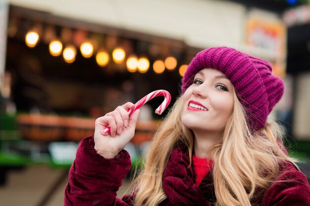 Bella donna bionda in posa con un bastoncino di zucchero di Natale