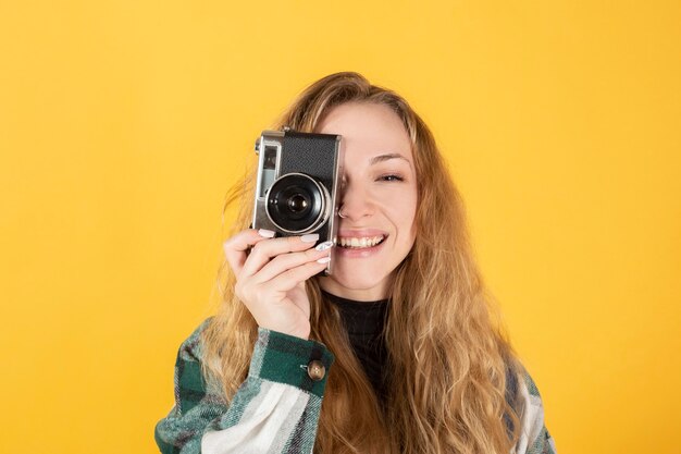 Bella donna bionda scatta foto con una vecchia macchina fotografica gialla