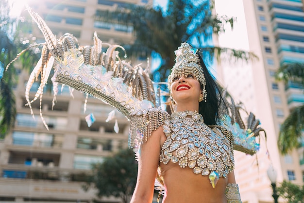 Bella donna brasiliana che indossa costumi di carnevale colorati e sorride durante la sfilata di carnevale in città.