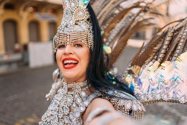 Bella donna brasiliana che indossa costumi di carnevale colorati e sorride durante la sfilata di carnevale in città.