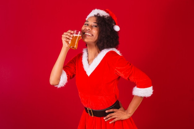 Bella donna brasiliana nera vestita da babbo natale mama claus che beve birra