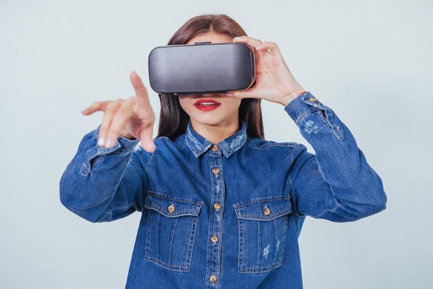 bella donna bruna che posa in studio indossando jeans indossando VRglasses cuffie di realtà virtuale