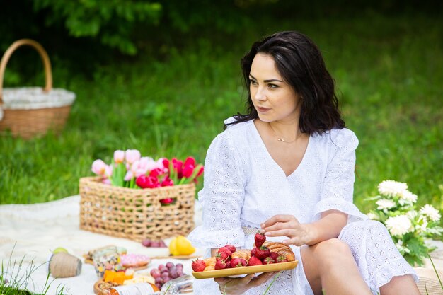 bella donna bruna che riposa nel parco seduta su una coperta da picnic Rilassante nella natura