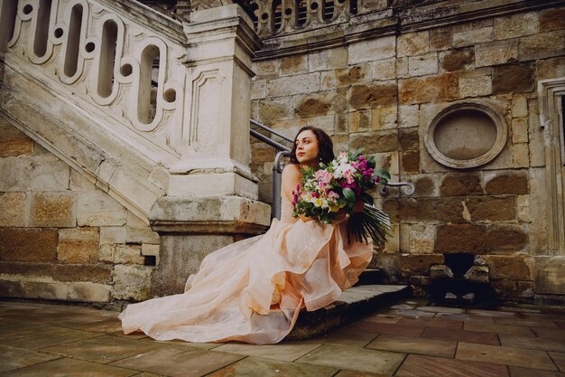 Bella donna bruna con un mazzo di fiori in un vestito rosa