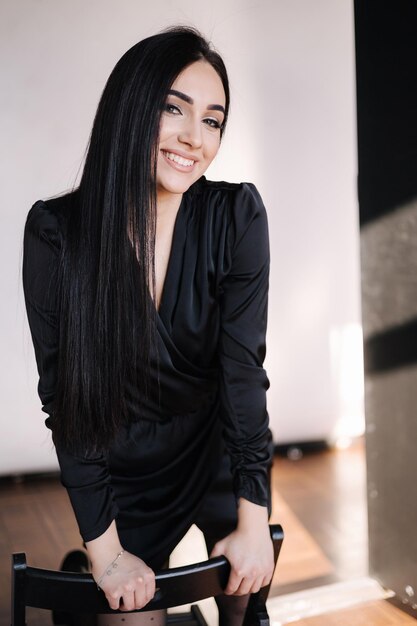 Bella donna bruna in elegante abito nero femmina con servizio fotografico in studio di trucco serale