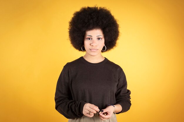 Bella donna capelli afro, guardando la telecamera sfondo giallo