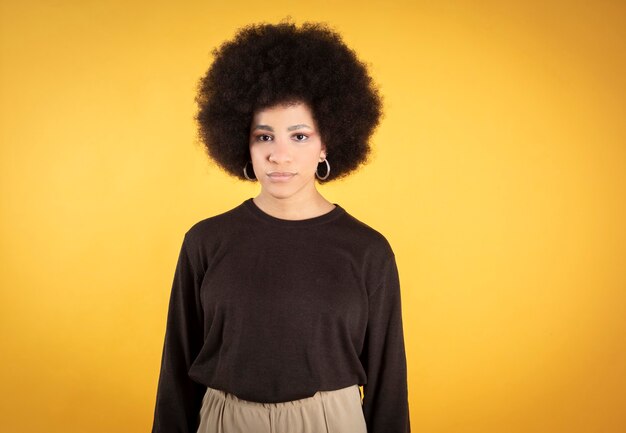 Bella donna capelli afro, guardando la telecamera sfondo giallo