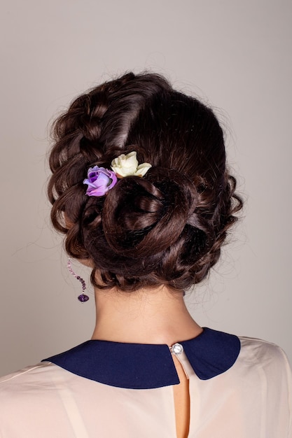 Bella donna castana indietro con stile di capelli da sposa elegante e fiori