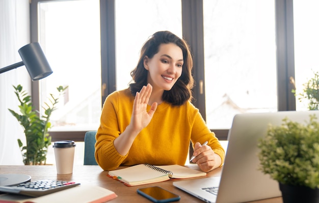 Bella donna casual felice che lavora su un computer portatile che parla con qualcuno in ufficio