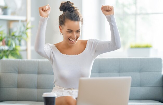 Bella donna casuale felice che lavora ad un computer portatile a casa.