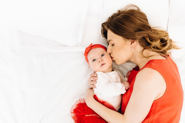 Bella donna caucasica che bacia sua figlia sveglia del bambino con spazio per testo