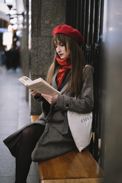 Bella donna caucasica che indossa cappotto berretto sciarpa e borsa con testo felicità seduta da sola sulla stazione della metropolitana di San Pietroburgo a leggere un libro Immagine con messa a fuoco selettiva ed effetto rumore