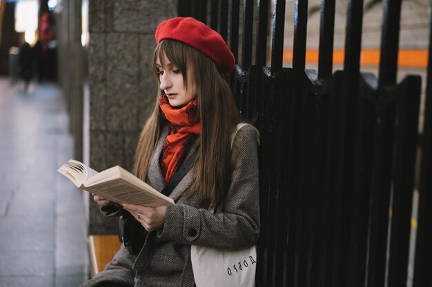 Bella donna caucasica che indossa cappotto berretto sciarpa e borsa con testo felicità seduta da sola sulla stazione della metropolitana di San Pietroburgo a leggere un libro Immagine con messa a fuoco selettiva ed effetto rumore