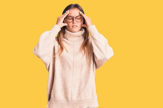 Bella donna caucasica che indossa un maglione invernale di lana che soffre di mal di testa disperato e stressato perché dolore ed emicrania. mani sulla testa.