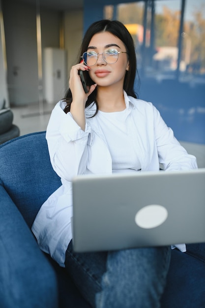 Bella donna caucasica che sogna qualcosa mentre si siede con un netbook portatile nel moderno bar caffetteria giovane affascinante freelance femminile che pensa a nuove idee durante il lavoro sul computer portatile