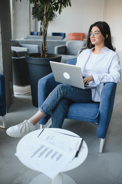 Bella donna caucasica che sogna qualcosa mentre si siede con un netbook portatile nel moderno bar caffetteria giovane affascinante freelance femminile che pensa a nuove idee durante il lavoro sul computer portatile