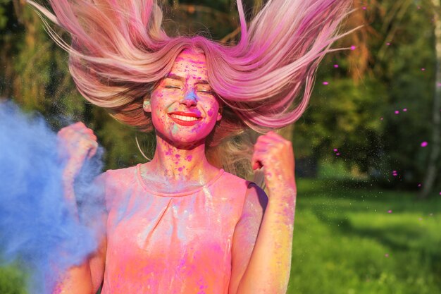 Bella donna caucasica con i capelli gonfiati dal vento che gioca con la vernice secca Holi