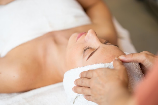 bella donna caucasica felice che si gode un massaggio alla testa al centro benessere