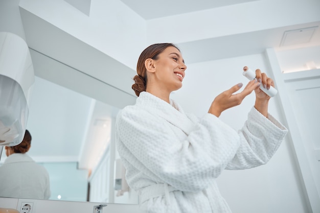 Bella donna caucasica sorridente in buona salute che si prende cura della sua pelle in bagno