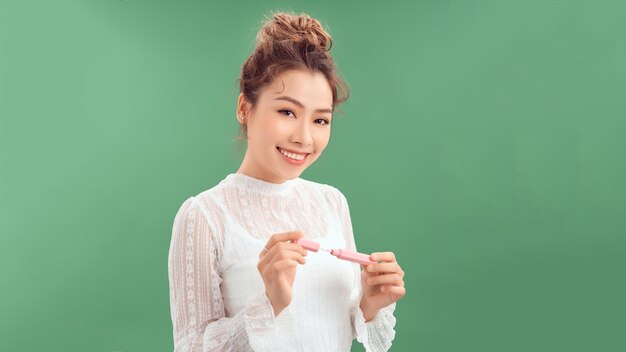 Bella donna che applica lucido per le labbra su uno sfondo verde trucco elegante