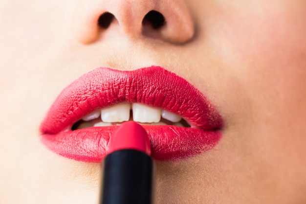 Bella donna che applica rossetto rosso sulle labbra