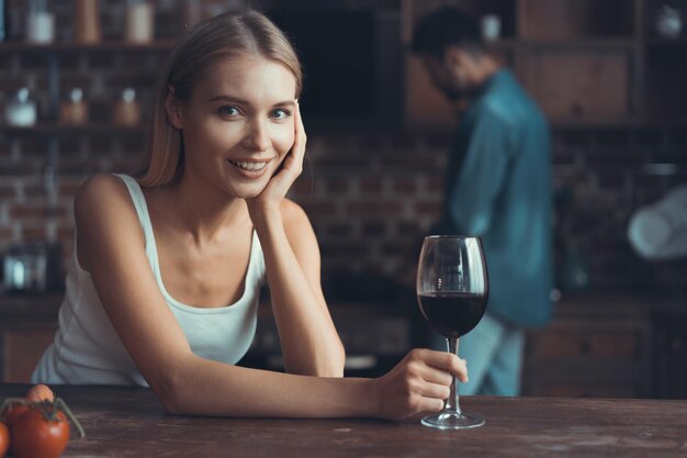 Bella donna che beve del vino a casa in cucina