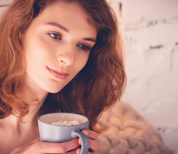 Bella donna che beve un caffè nel suo letto Concetto di stile di vita