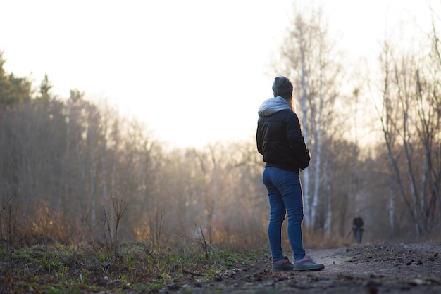 Bella donna che cammina nel parco e si gode la soleggiata passeggiata nella foresta di primavera